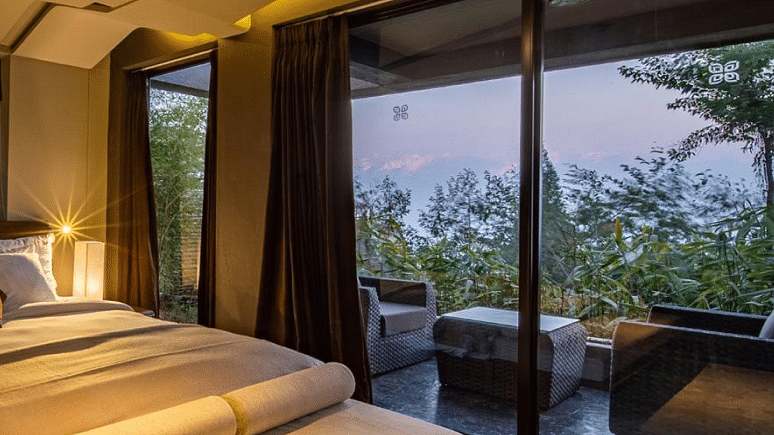 A bedroom with large window giving a view of a sitting area on the deck | Kavya Resort and Spa, Nagarkot